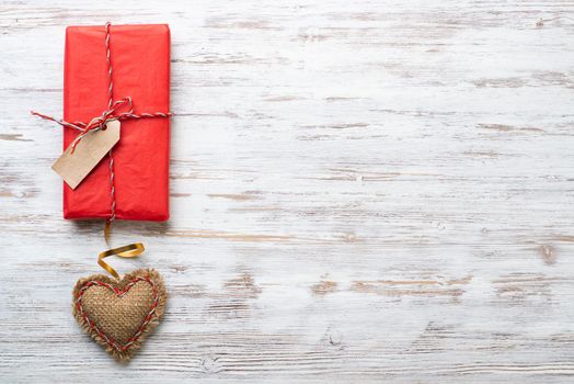 Flat lay cute composition with handmade fabric red hearts. Red gift box on wooden table. Happy birthday or anniversary congratulation. Romantic love story template with copy space.