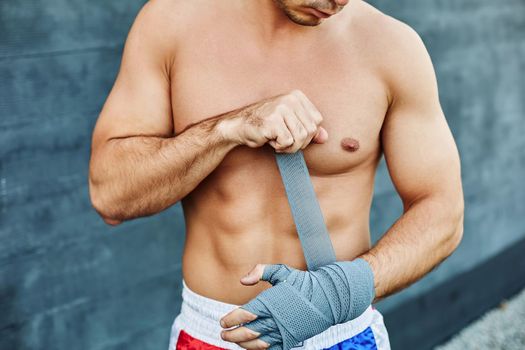 Close up of fit man wearing bandage on his hand. Nude torso