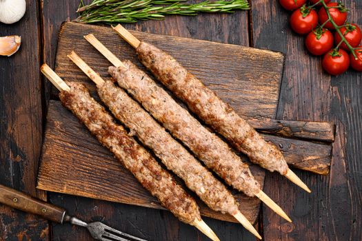 Turkish meat kebab set, on serving board, on old dark wooden table background, top view flat lay