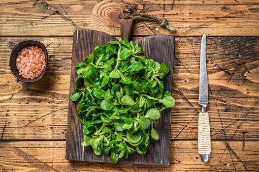 Fresh Raw green lambs lettuce Corn salad leaves on a wooden cutting board. wooden background. Top view.