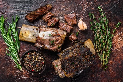 BBQ Grilled short beef ribs on a kitchen table. Dark background. Top view.