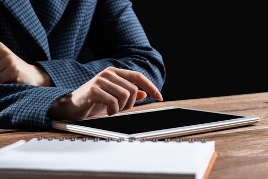 Businesswoman using tablet computer at desk. Close up woman hand pointing on touchscreen. Online stock trading and financial analytics. Digital technology in strategy planning and company management