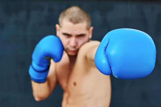 Boxer in blue gloves on the street. He looks into the camera. Beat in the camera