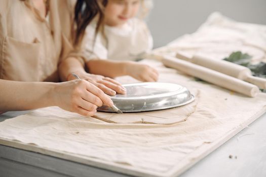 Woman and girl kneading clay. Family make art product at table in pottery workshop. Mother with daughter.