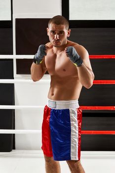 Boxer in gloves warming up in the ring. naked torso. He looks into the camera
