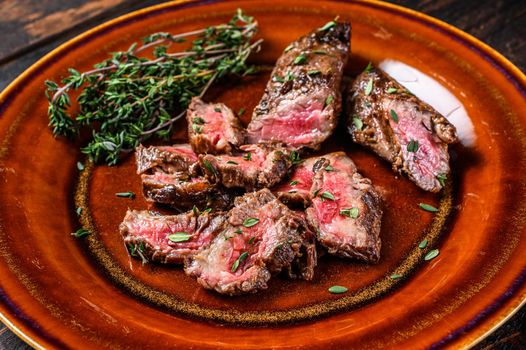 Sliced Grilled barbecue brisket steaks slices on a rustic plate. Dark wooden background. Top view.