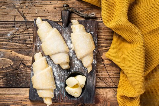 Raw uncooked french croissant on a wooden board. Wooden background. Top view.