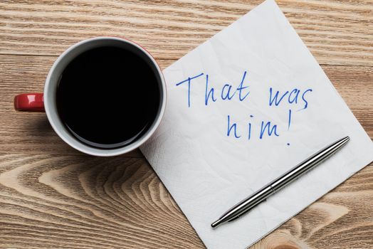 Coffee cup pen and napkin with words on wooden table