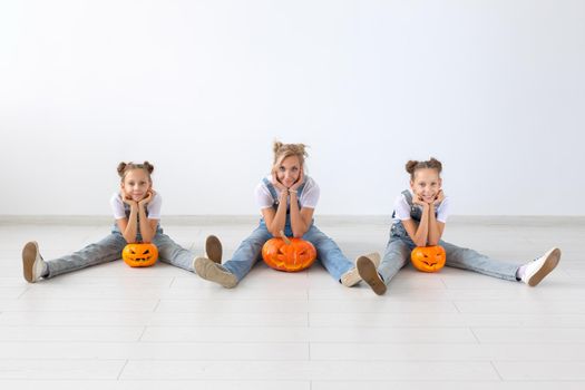 Happy halloween and holidays concept - A mother and her daughters with pumpkins. Happy family preparing for Halloween