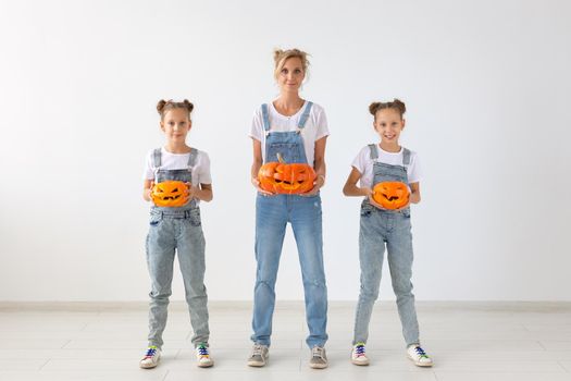 Happy halloween and holidays concept - A mother and her daughters with pumpkins. Happy family preparing for Halloween