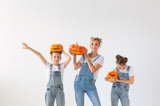 Happy halloween and holidays concept - A mother and her daughters with pumpkins. Happy family preparing for Halloween