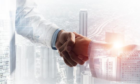 Close-up of the handshake between the two medics. Against the backdrop of the cityscape