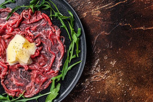 Slice Of beef Carpaccio, arugula and Parmesan. Dark background. Top view. Copy space.