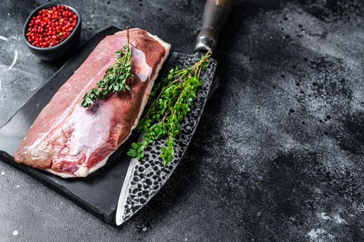 Raw duck breast fillet on a marble board. Black background. Top view. Copy space.