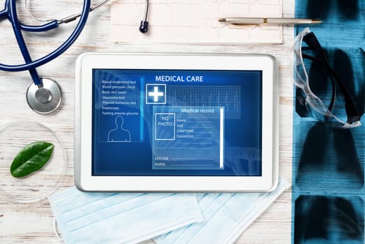 Laboratory patient examination in doctors office. Tablet computer with medical app interface on screen. Stethoscope, x-ray image and cardiogram on wooden desk. Medical diagnostics and examination