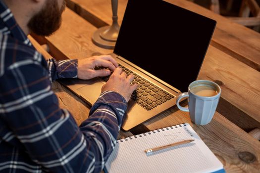 Cropped image of young man chatting via net-book during work break in coffee shop, male sitting in front open laptop computer with blank copy space screen for your text message or advertising content