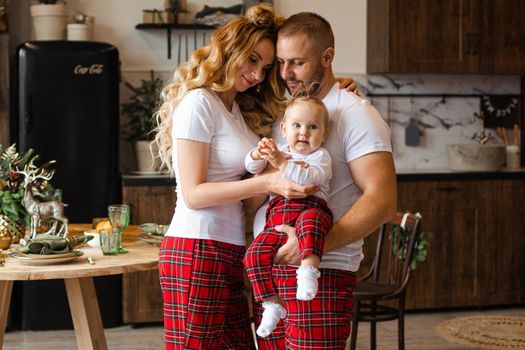 Mum and dad on the kitchen with their little child in the same sleepwear