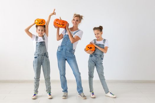 Happy halloween and holidays concept - A mother and her daughters with pumpkins. Happy family preparing for Halloween