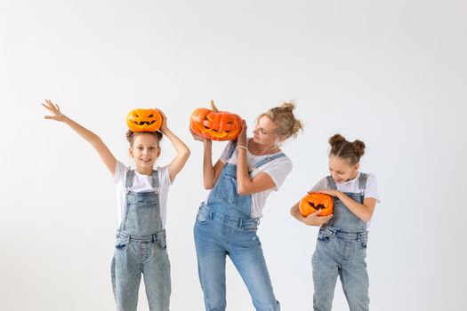 Happy halloween and holidays concept - A mother and her daughters with pumpkins. Happy family preparing for Halloween