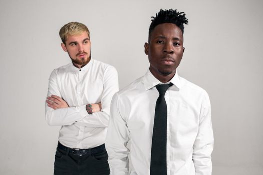 Friends. Two guys in white shirts and dark pants posing in the studio on a white background. Copy space. Belt portrait