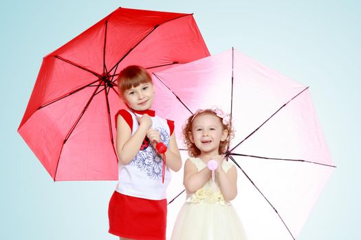 Two charming little girls, little sister and the eldest, sheltered from rain or sun under umbrellas.