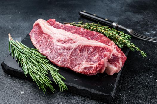 Raw Striploin steak or New York steak beef meat cut. Black background. Top view.