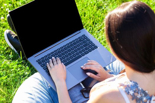 Close up hands on keyboard. Woman working on laptop pc computer with blank black empty screen to copy space in park on green grass sunshine lawn outdoors. Mobile Office. Freelance business concept