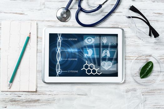 Human genetic research in modern medical laboratory. Tablet computer with DNA helix structure on screen. Stethoscope and cardiogram on wooden desk. Medical diagnostics and patient genome testing.