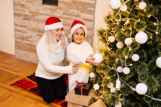 Daughter with her mother near the Christmas tree.