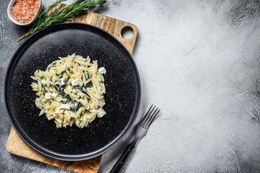 Spinach and Feta orzo pasta on a plate. White background. Top view. Copy space.