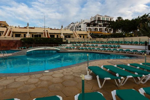 A group of lawn chairs sitting next to a pool of water. High quality photo