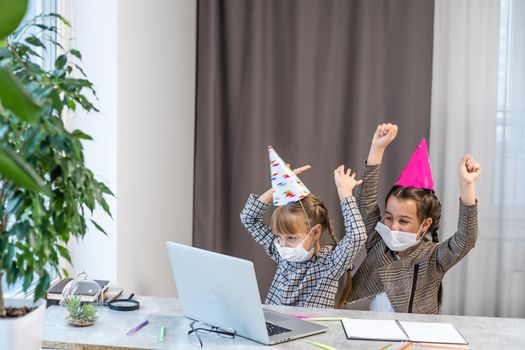 Kids online birthday party. Little girls in dresses, hat celebrate holiday with friends. Conference,video call in laptop, computer. Quarantine, coronavirus pandemic covid-19.