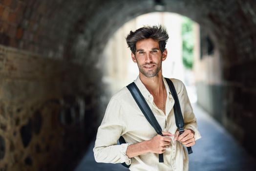 Young man sightseeing enjoying the streets of Granada, Spain. Male traveler carrying backpack in urban background.