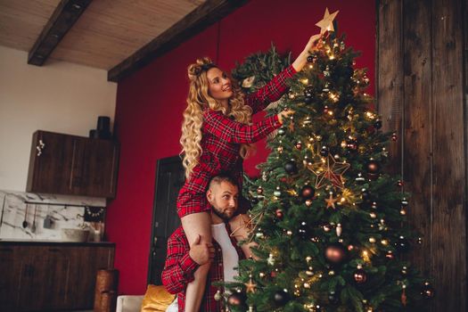 Attractive woman decorates christmas tree with a man in the living room