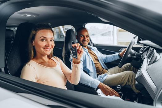 Happy excited couple or family buying a new car and showing keys