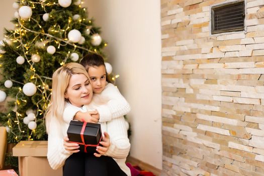 Daughter with her mother near the Christmas tree.