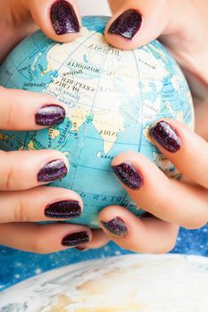 woman hands with purple manicure holding Earth ball, global planet issues concept close up