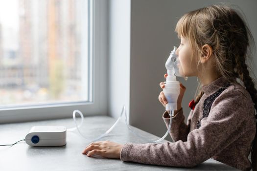 Little girl making inhalation with nebulizer at home. child asthma inhaler inhalation nebulizer steam sick cough concept Horizontal