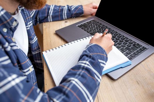 Casual business man or freelancer planning his work on notebook, working on laptop computer with smart phone, cup of coffee on table at coffee shop or home office, working from cafe concept