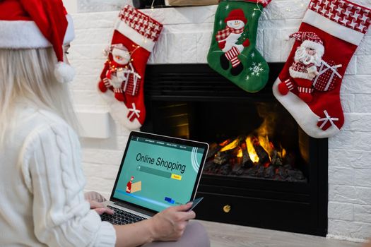 Christmas online shopping. Female buyer with laptop, copy space on screen. Woman buys presents, prepare to xmas eve, sitting among gifts boxes and packages. Winter holidays sales