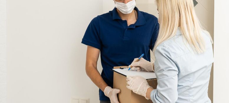 A courier in a protective mask and a glove delivers food to a woman. Volunteer delivers fresh food to those in need