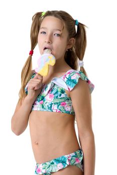 Beautiful girl in a swimsuit, with ice cream in her hand. Beautiful little girl of ten years old with pigtails posing in the studio on a white background. Happy girl having summer vacation