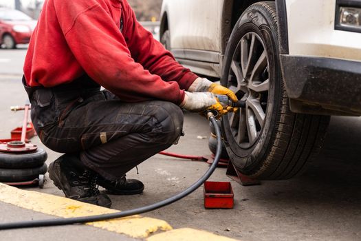 Car mechanic removing wheel nuts to check brakes
