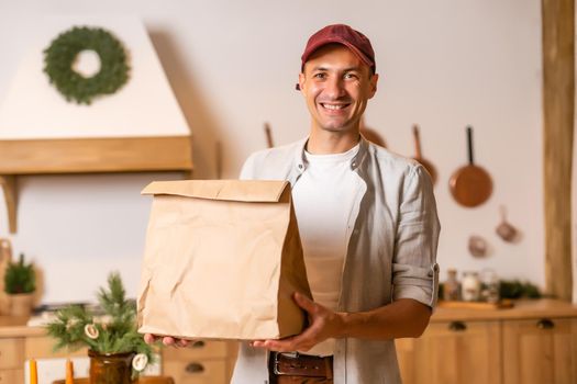 a delivery man with a package of food stands in a Christmas interior