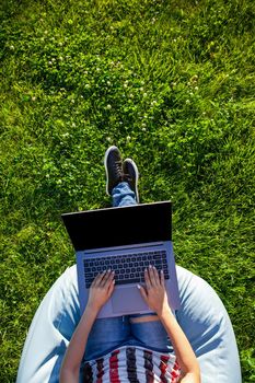 Top view hands on keyboard. Woman working on laptop pc computer with blank black empty screen to copy space in park on green grass sunshine lawn outdoors. Mobile Office. Freelance business concept