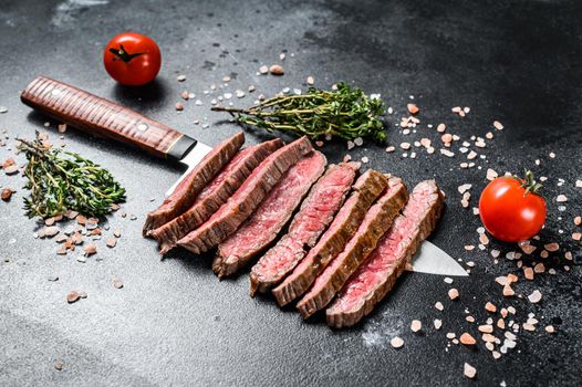 Grilled and sliced Flank rare steak. Marble beef meat. Black background. Top view.