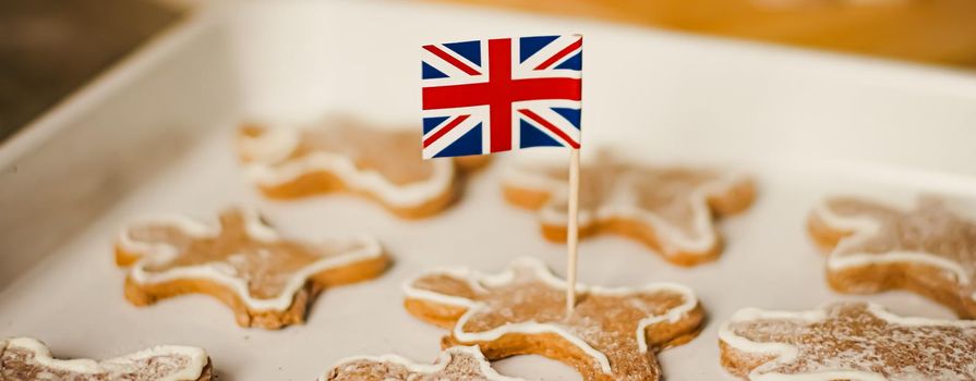 British holiday and Christmas baking concept. Union Jack flag of Great Britain and gingerbread men biscuits in the kitchen in England.