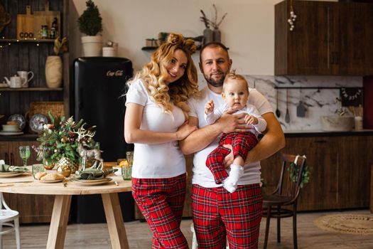Mum and dad on the kitchen with their little child in the same sleepwear