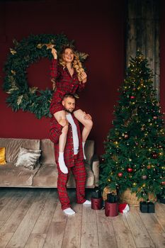 Attractive girl and her boyfriend decorates christmas tree in the living room