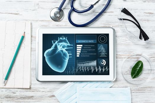 Medical diagnostics in hospital. Tablet computer with medical app interface on screen. Doctor workplace with stethoscope and cardiogram on wooden desk. Digital technology in cardiology clinic.